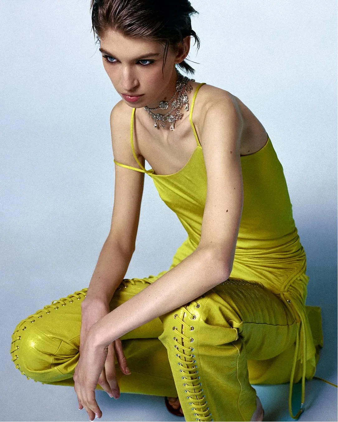 Model in yellow satin top and lace-up leather trousers