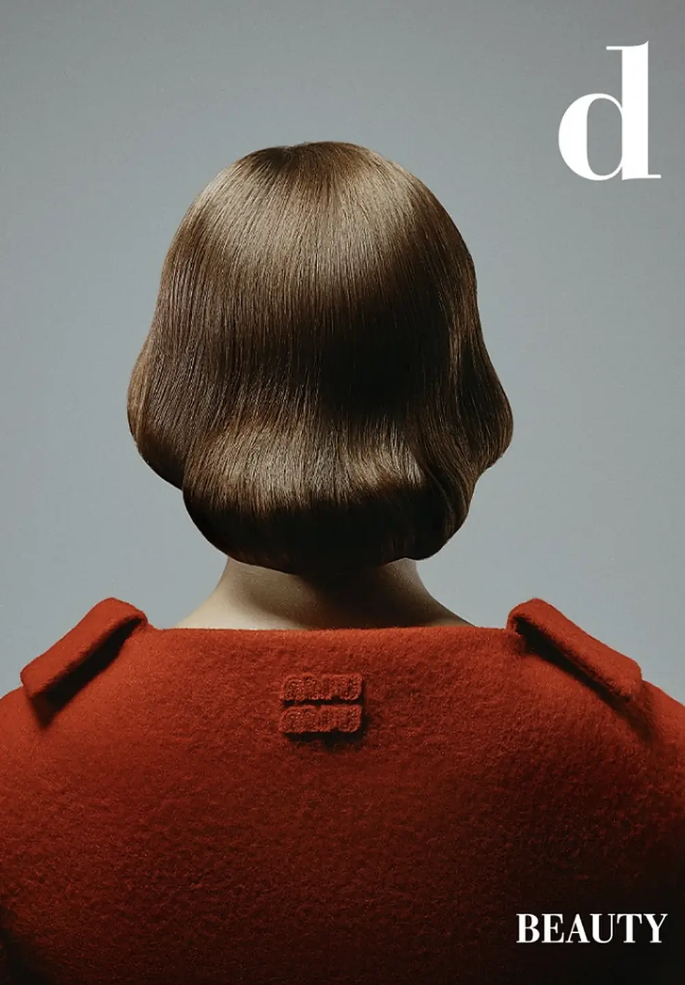 Back of a model with a glossy brown bob and a red wool coat, on the cover of D Beauty