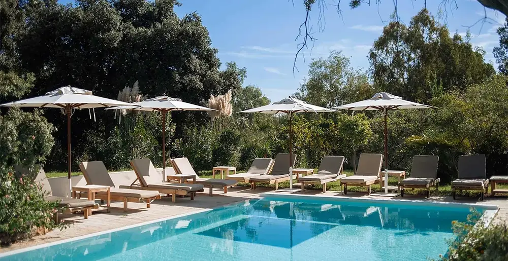 Lanthia Resort pool with parasols and mountains behind